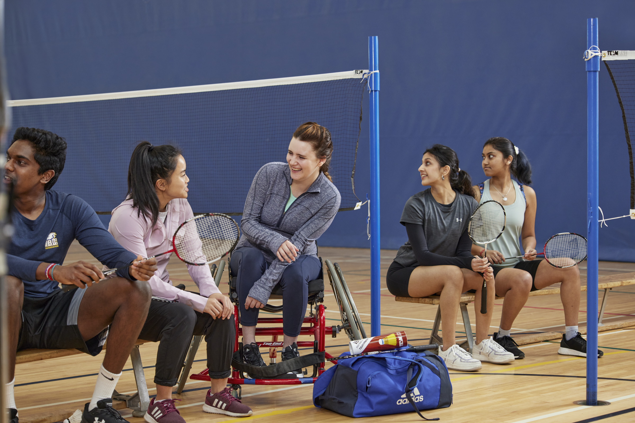 students sitting in gym with tennis raquets